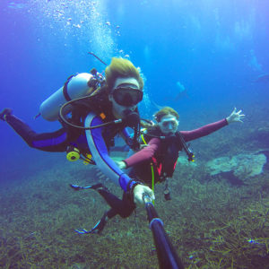 Underwater scuba diving selfie shot with selfie stick. Deep blue