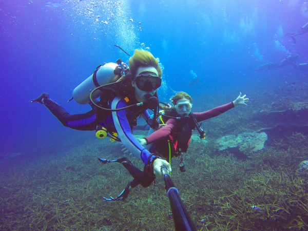 Underwater scuba diving selfie shot with selfie stick. Deep blue